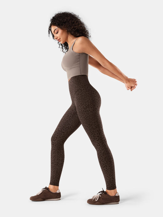 Easelyn Built-In Resistance Band Leggings in Brown Leopard, full-body side view stretching the arms back
