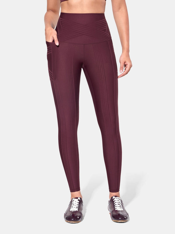 Easelyn Built-In Resistance Band Leggings in Redwood, front view from the waist down with a hand in the side pocket, tonal band lines and crossover waistband