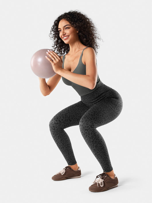 Easelyn Built-In Resistance Band Leggings in Gray Leopard, lifestyle squat holding a small exercise ball