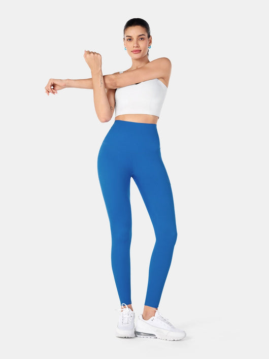 Easelyn Built-In Resistance Band Leggings in Power Blue, full-body front view stretching one arm, solid reverse side