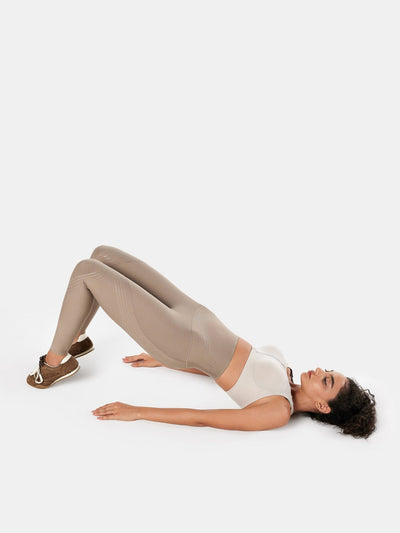 Easelyn Postpartum Recovery Compression Leggings in Tan, glute bridge on the floor, side view of the high waistband and leg lines