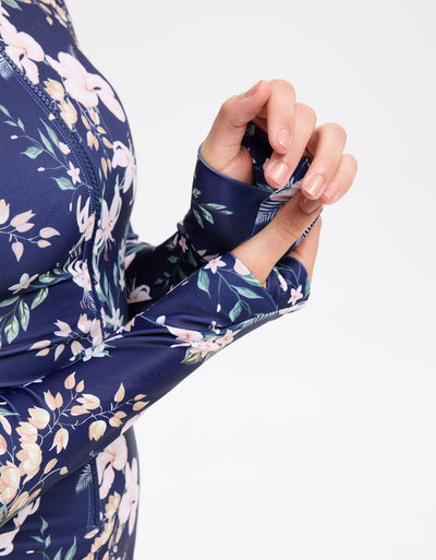 Easelyn UPF 50+ Long-Sleeve One-Piece Swimsuit in Tropical Navy Floral, close-up of the long sleeve cuff with the thumb through the thumbhole