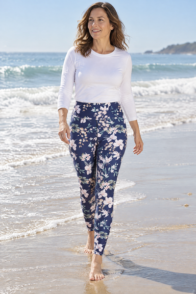 Easelyn UPF 50+ High-Rise Swim Leggings in Tropical Navy Floral, a woman in her 40s with a natural build walking barefoot along the wet